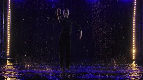 Silhouette of a man performing an element of bachata dance under rain. Man Stock Footage 137994944