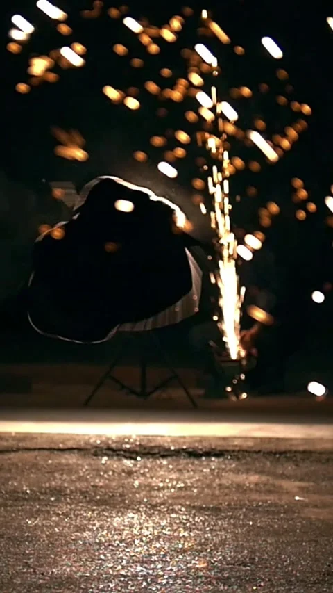 Silhouette of man performing martial elements through the sparks from grinder at Stock Footage 346756502
