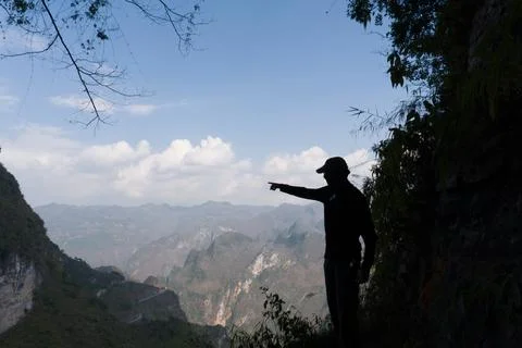 Silhouette of a man pointing toward distant mountains Stock Photos