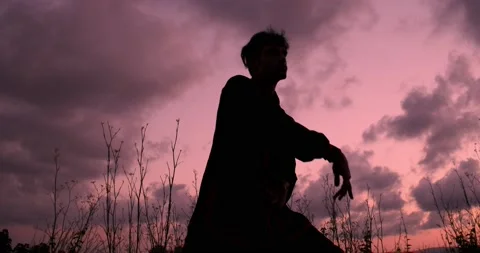 Silhouette of a man practicing chikung during a beautiful sunset Stock Footage 136026811