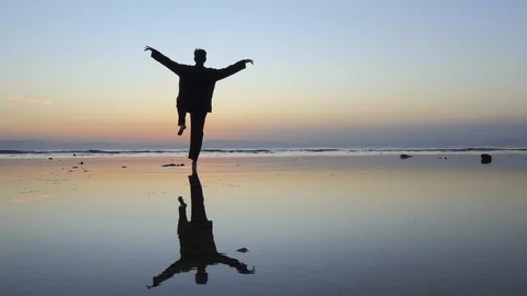 Silhouette of man practicing the elements of qigong at sunset by the sea Stock Footage 126000264
