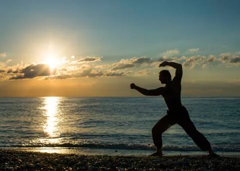 Silhouette of a man practises wing chun on the beach Stock Photos