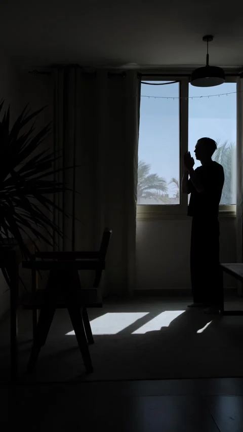 Silhouette man praying by window, seeking guidance and answers during Stock Footage 346244056
