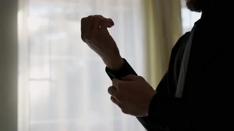 Silhouette of a man putting on his jacket in dark room on the background of the Stock Footage 230477640