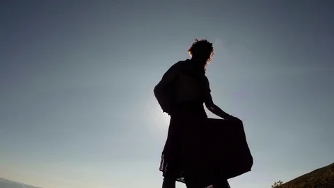 The silhouette of a man in the rays of the sun spreads the veil and sits down in Stock Footage 77785121