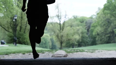 Silhouette of a man running running through a park in slow motion Stock Footage 63099144