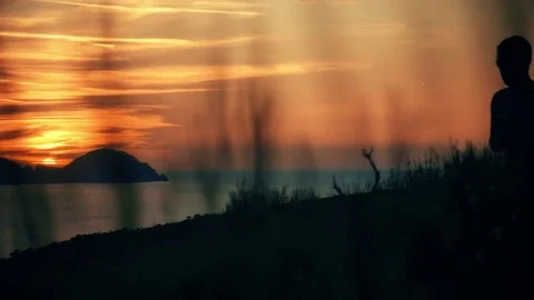 Silhouette of a man running on top of a mountain on an island at sunset with the 스톡 동영상 80051280