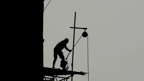 Silhouette of Man on scaffolding using traditional pulley hoist Vidéo 88841357
