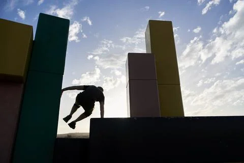 Silhouette of a man seen jumping between concrete blocks practicing parkour Foto stock