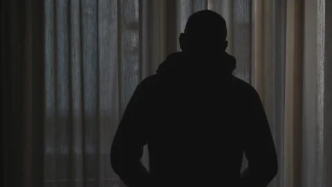 Silhouette of a man in silhouette looking through a window curtain Stock Footage 172445643