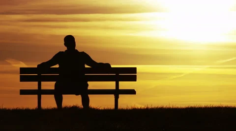 Silhouette man sitting on a bench at sunset, then walks away, in slow motion Video stock 62843667