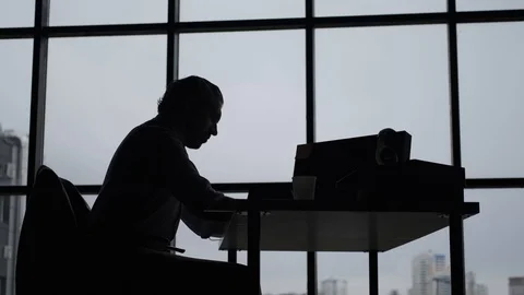 Silhouette of a man sitting at a table in the office. Stock Footage 107331387