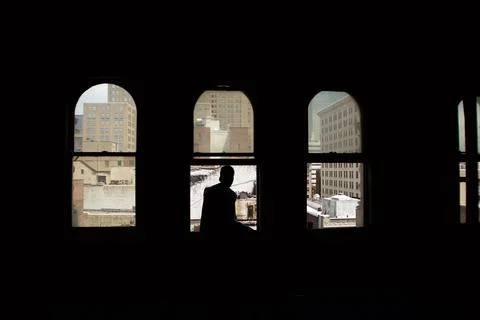Silhouette of man sitting in the window of an empty apartment building Stock Photos