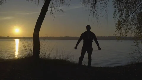 Silhouette of a Man Skillfully Repeating the Kata of Karate by the River Early Stock Footage