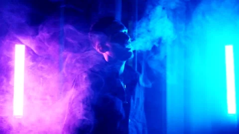 Silhouette of man smoking a cigarette on dark blue background Stock Footage 139499641