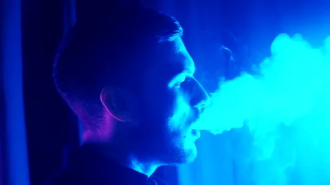 Silhouette of man smoking a cigarette on dark blue background Stock Footage 139499696