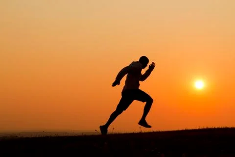 Silhouette of a man sprinting during sunset Stock Photos