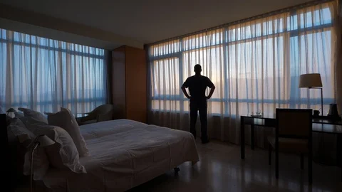 Silhouette of man standing alone against window in empty room Stock Footage 125183886