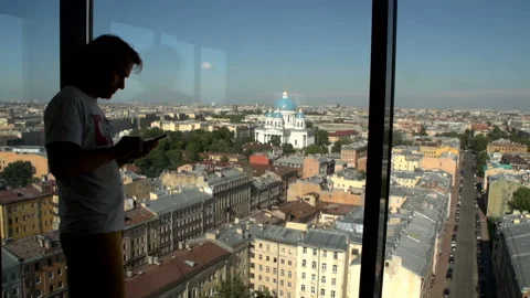 Silhouette man standing and using mobile phone at window. Stockbeeldmateriaal 112339099