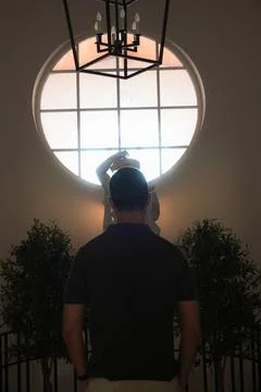 Silhouette of man standing in front of large circular window indoors Stock Photos