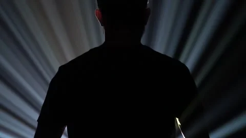 Silhouette of a man standing in front of a light beam Stock Footage 170833074