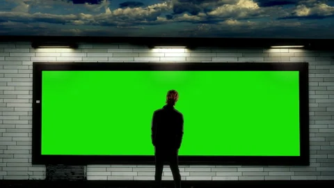Silhouette Man Standing Before Large Green Billboard Mockup In Urban Wall Stock Footage 341961591