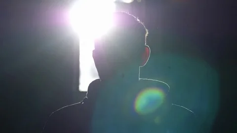 Silhouette of man standing by large window looking over the sun with lense flare Stock-Footage 82850268