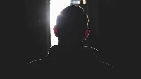 Silhouette of man standing by large window looking over the sun with lense flare Видео 82850315
