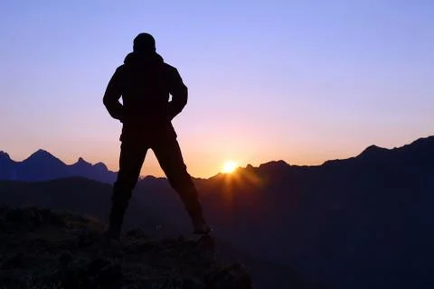 Silhouette of man standing on the mountain face to sunrise Stock Photos