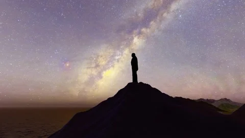 Silhouette of a man standing on the top of the mountain at night looking at  Stock Footage 234245679