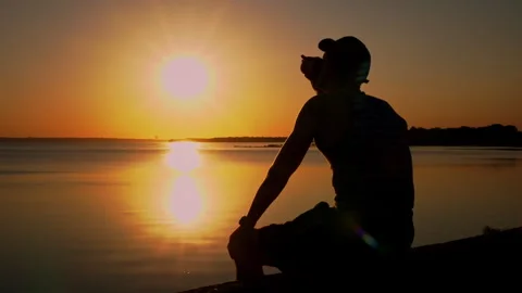Silhouette of a Man at Sunset Drinking Coffee Alone Stock Footage 250241287