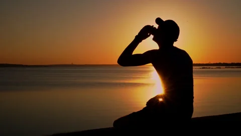 Silhouette of a Man at Sunset Drinking Coffee Alone Stock Footage 252797465