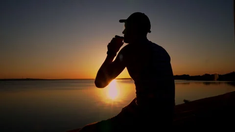Silhouette of a Man at Sunset Drinking Coffee Alone Stock Footage 252797679