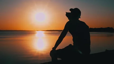 Silhouette of a Man at Sunset Drinking Coffee Alone Stock Footage 252797804
