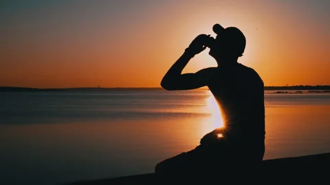 Silhouette of a Man at Sunset Drinking Coffee Alone Stock Footage 252797880