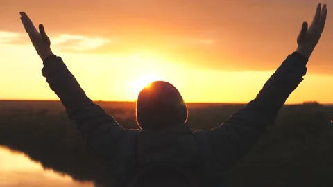 Silhouette of a man at sunset with raised hands against the sunset. A man dreams Stock Footage 146244181
