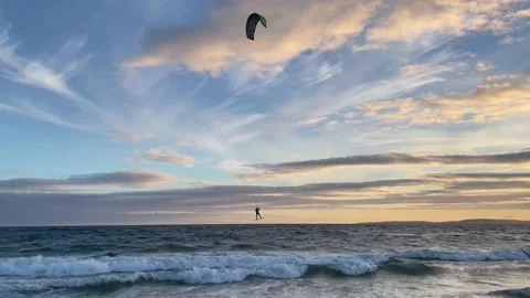 A silhouette of a man surfing with kite on waves and jumping out of the Stock Footage 161653727