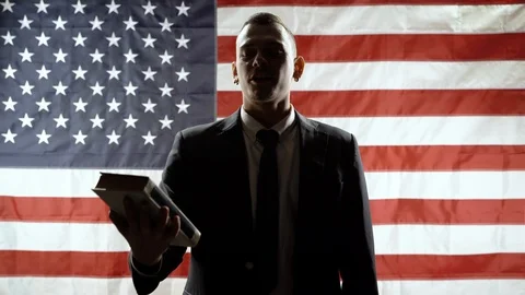 Silhouette of a man taking an oath while holding his hand on the Constitution Stock Footage 119465983