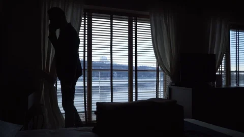 Silhouette of a man talking on cell phone while standing in a hotel room by the Stock-Footage 101228091