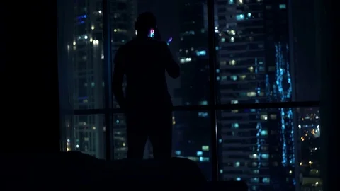 Silhouette of man talking on cellphone by window in bedroom at night Vidéo 71143218