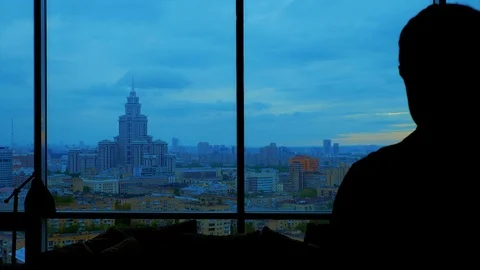 Silhouette of man thoughtfully looking at cloudy city Stock Footage 103200082
