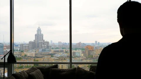 Silhouette of man thoughtfully looking at cloudy city Stock Footage 103200091