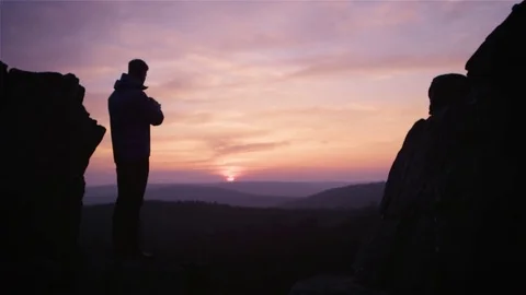 Silhouette of a man trying to capture the setting sun with his camera Stock-Footage 81536860