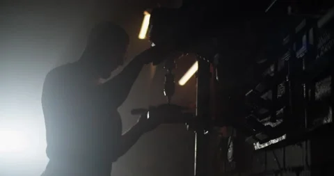 Silhouette of man using drilling machine in dark workshop Stock Footage 259390290