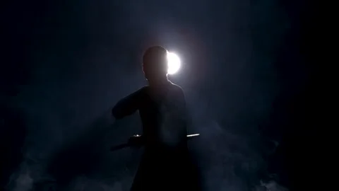 Silhouette of a Man Using Nunchucks in the Darkness Surrounded by Smoke Stock Footage 270299477