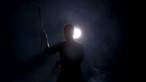Silhouette of a Man Using Nunchucks in the Darkness Surrounded by Smoke Stock Footage 270299872