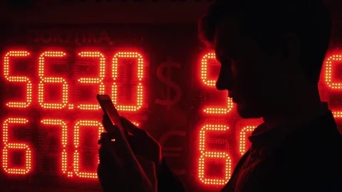 Silhouette of man using smartphone at night standing near display with exchange Stock Footage 80009474
