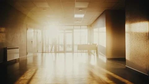 Silhouette of man walking and talking on the phone in hall at bright sun lights Stock Footage 169944978