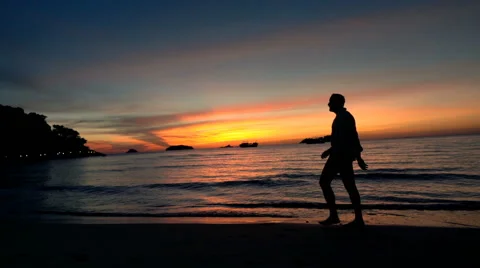 Silhouette of man walking on beach during sunset, super slow motion 120fps Stock Footage 63209426