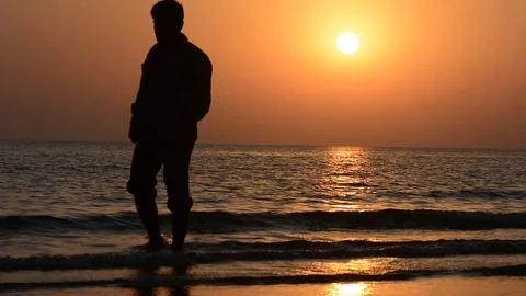Silhouette of man walking on beach during with golden sun Stock Footage 113672906